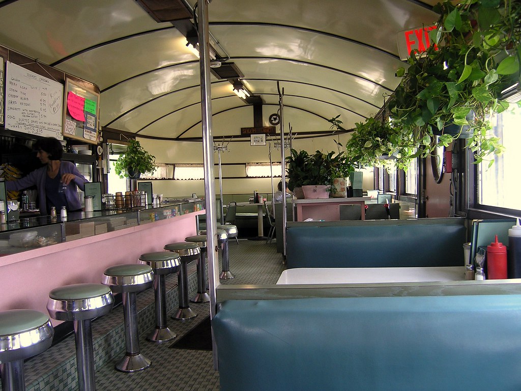 interior diner with pastel booths & counter, lined with plants